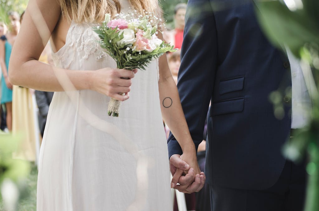 Beautiful outdoor wedding ceremony showcasing a bride and groom holding hands with a bouquet of flowers.