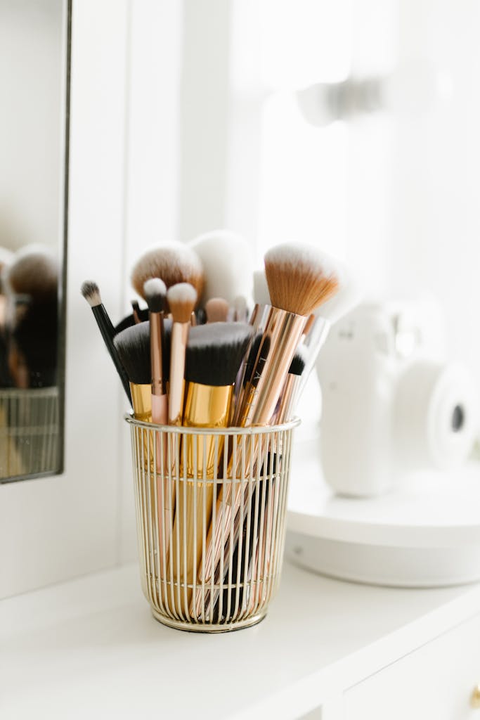 Stylish makeup brushes in a gold holder on a white vanity, perfect for beauty enthusiasts.