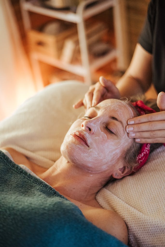 Adult lady getting massage with mask on face while lying in spa salon