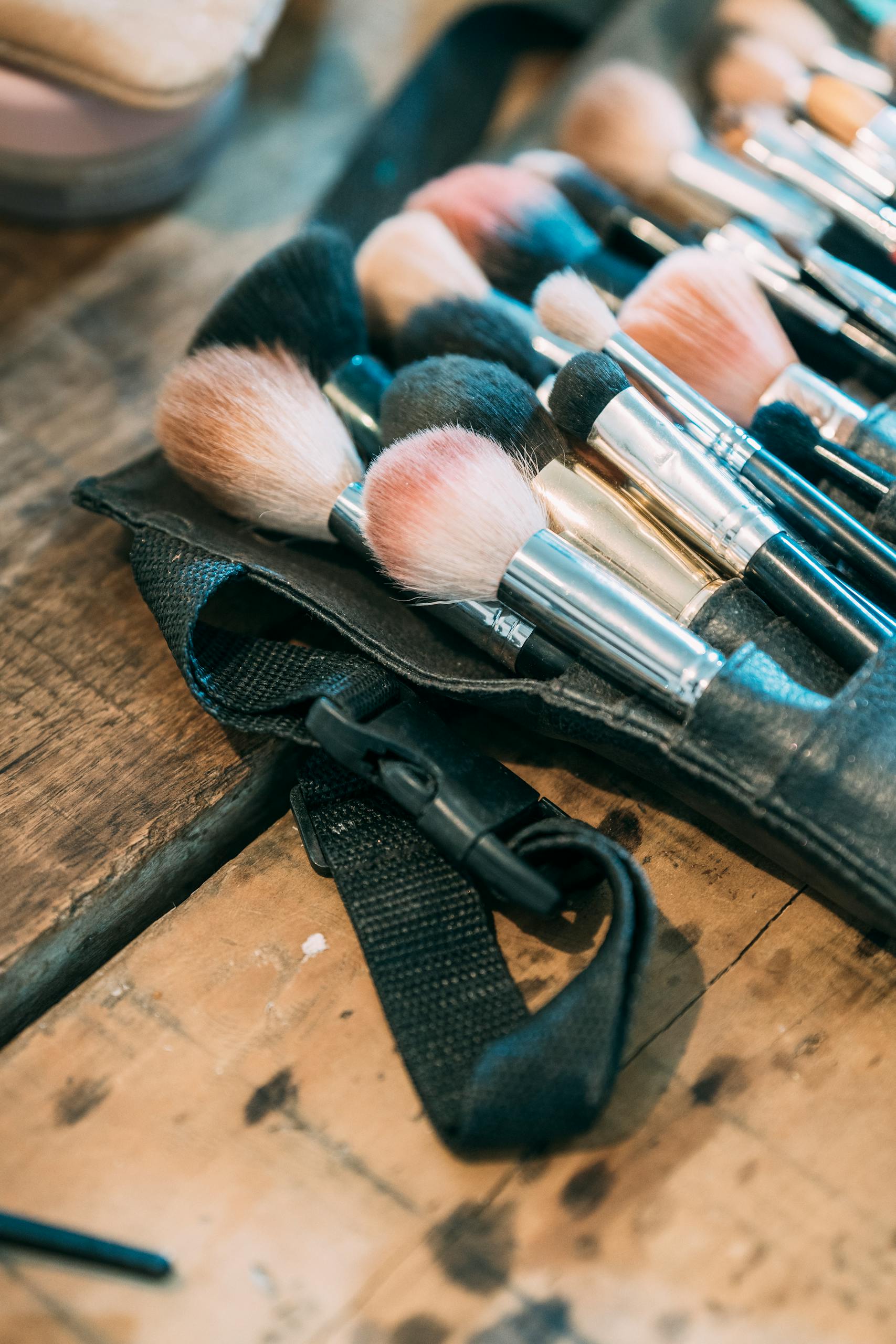 Close-up of various makeup brushes arranged on a wooden surface, highlighting textures and diversity.